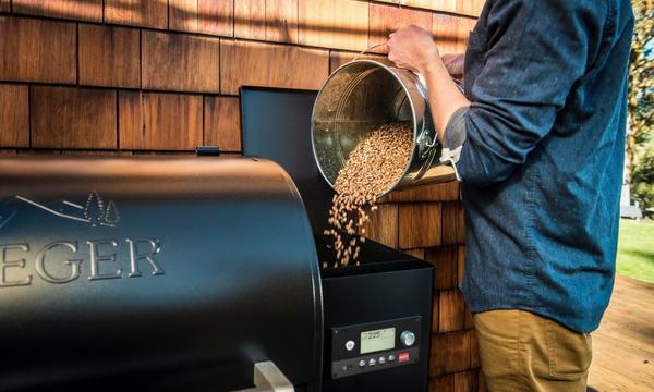 Man adding pellets to a Traeger Wood Pellet grill hopper